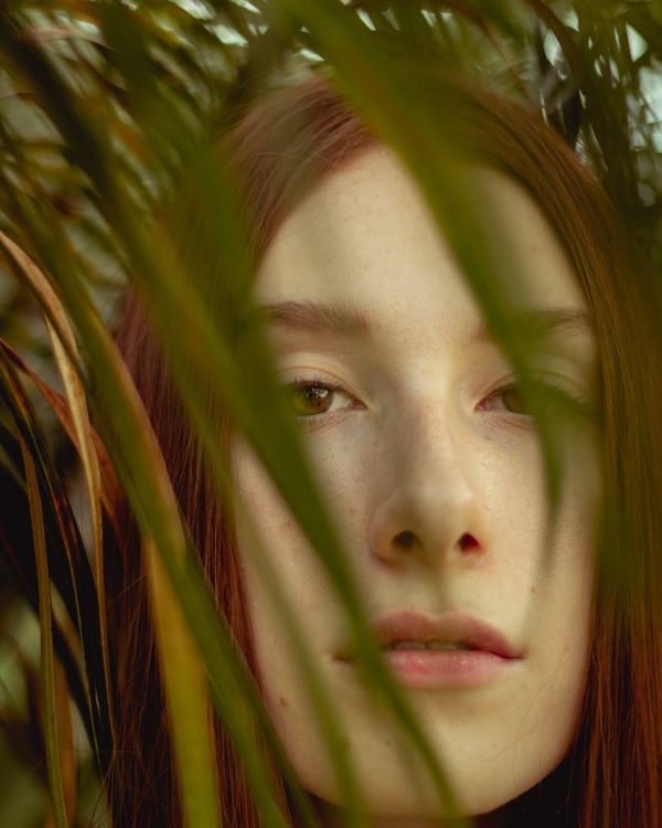 Woman peacefully closing her eyes in a calm, green-toned environment.